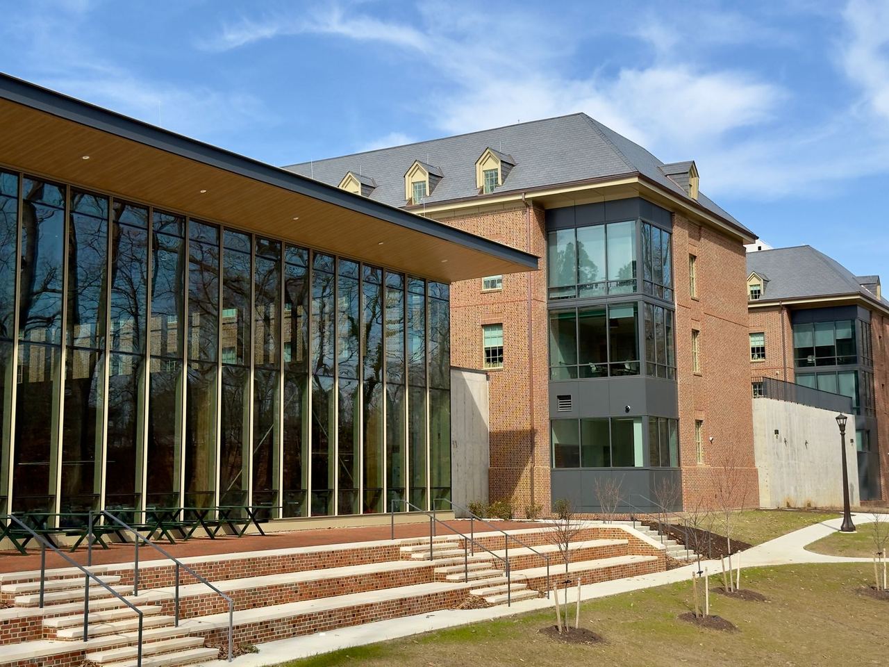 A modern brick and glass academic building on a university campus under a clear sky