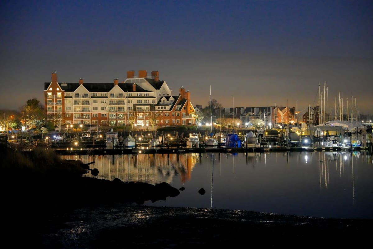 Office buildings above a marina of moored sailboats at twilight