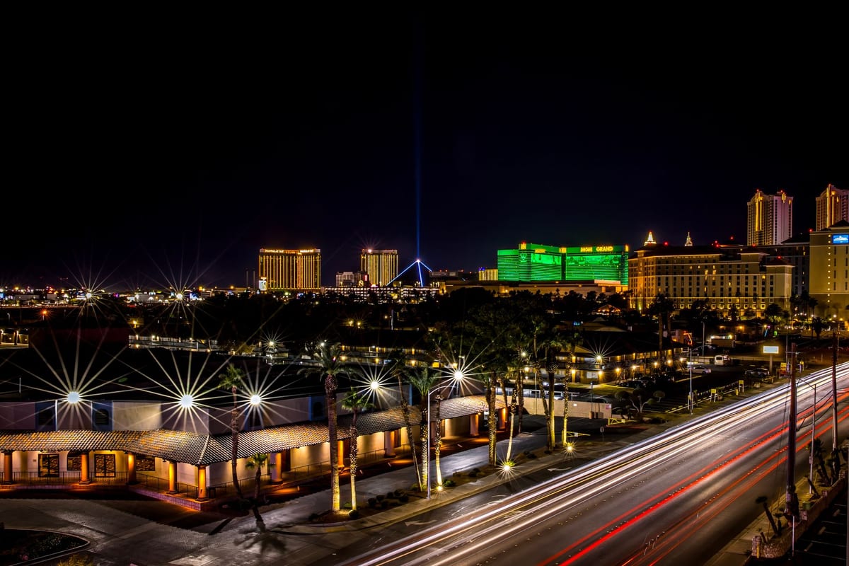 A boulevard of illuminated hotels and casinos at night with light trails along it