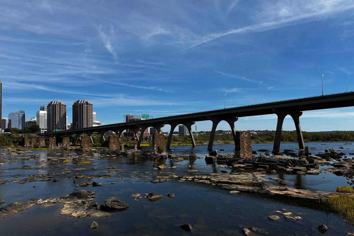 A downtown skyline behind a long historic bridge over a wide river under a clear sky
