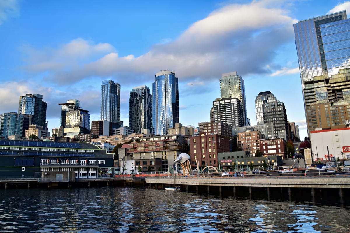 Glass towers along a working waterfront under a bright blue sky