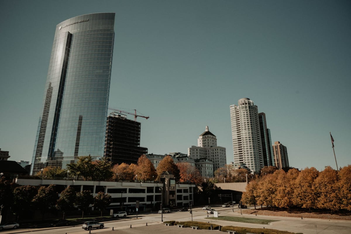 A lakeside downtown of mixed towers framed by trees in autumn color